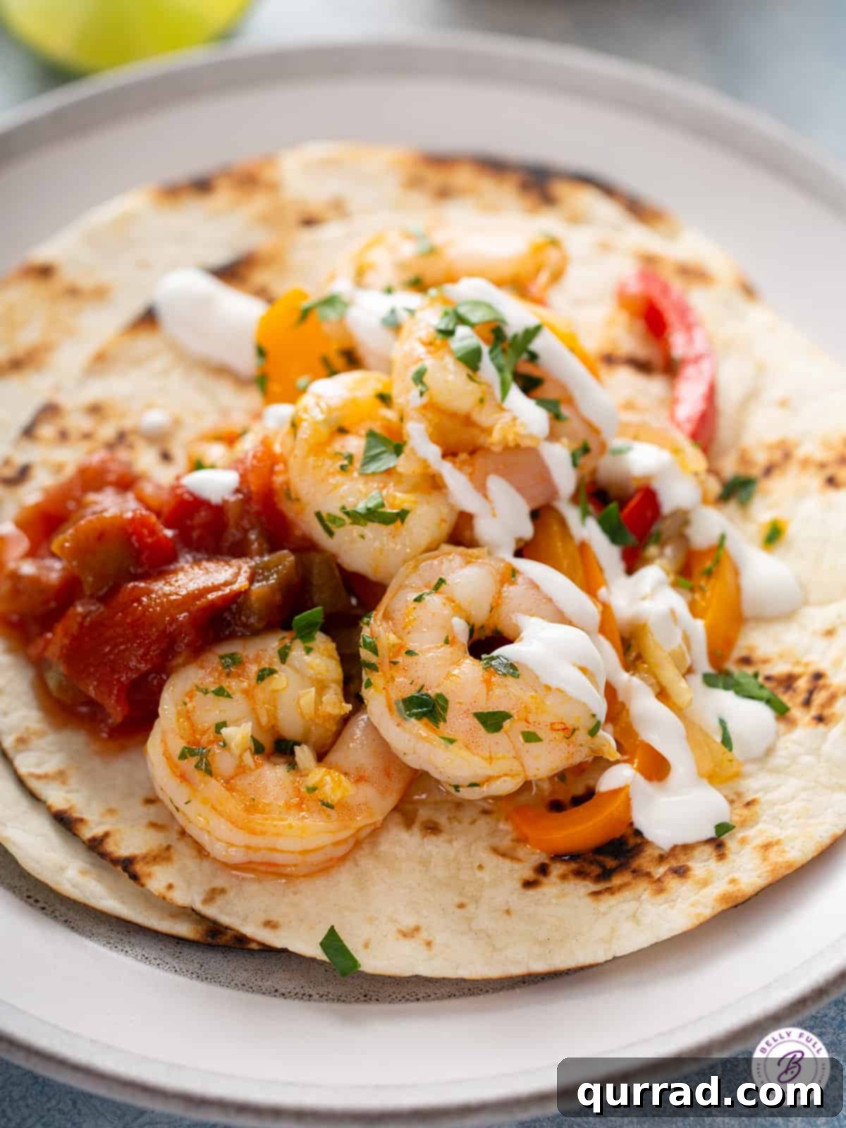 Sizzling Shrimp Fajitas 9 Close-up of a single shrimp fajita, showing the cooked shrimp, peppers, and sour cream drizzle inside a warm tortilla.