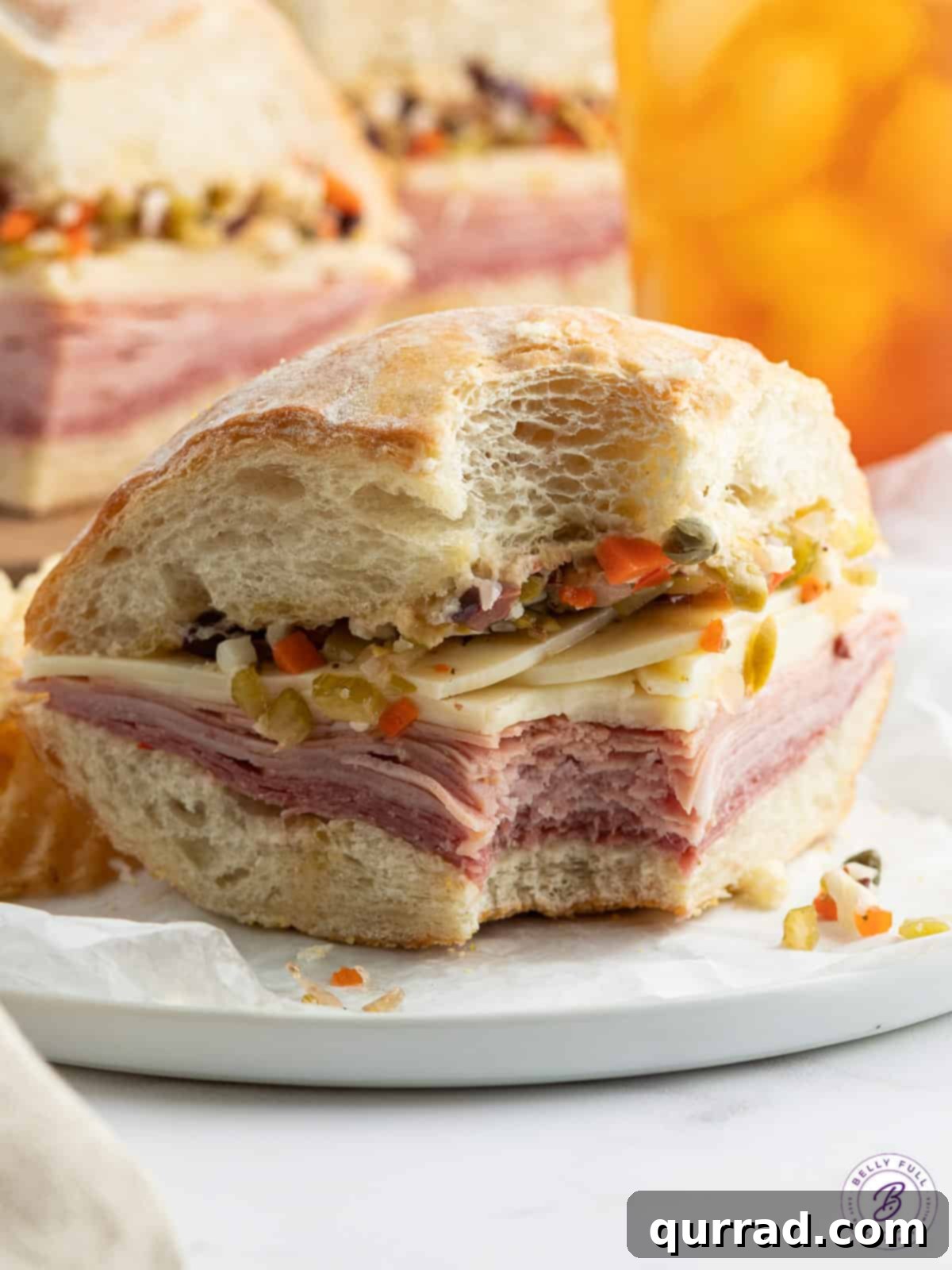 Front view of a Muffuletta sandwich with a bite taken, showcasing its dense filling.