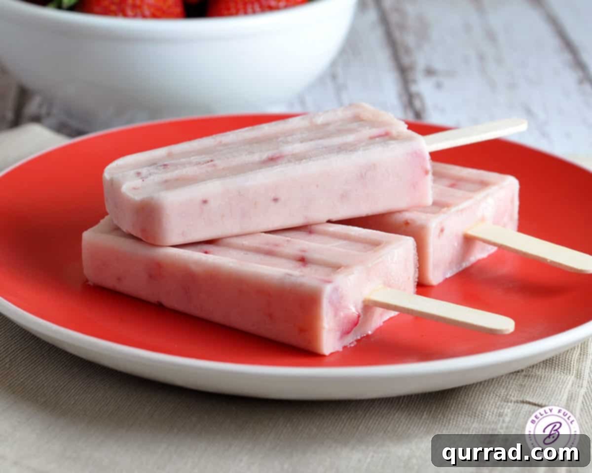 Sweet Strawberry Swirl Yogurt Pops 3 Three perfectly stacked strawberry popsicles on a bold red plate, showcasing their inviting pink hue and creamy texture.