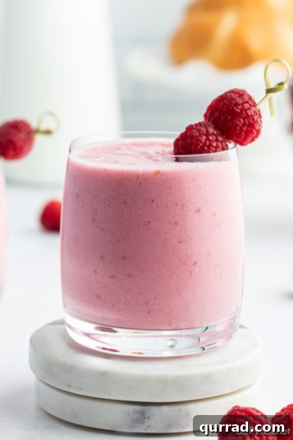 Refreshing Raspberry Lassi 3 straight on picture of raspberry lassi in glass tumbler with fresh raspberries on toothpick