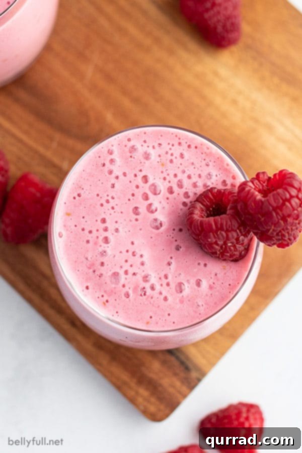 Refreshing Raspberry Lassi 4 overhead raspberry lassi in glass with fresh raspberries on wood cutting board