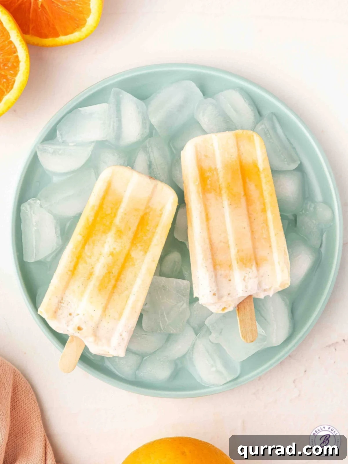 Citrus Cream Dream 9 Overhead view of two homemade orange creamsicles on a white plate, ready to be enjoyed.