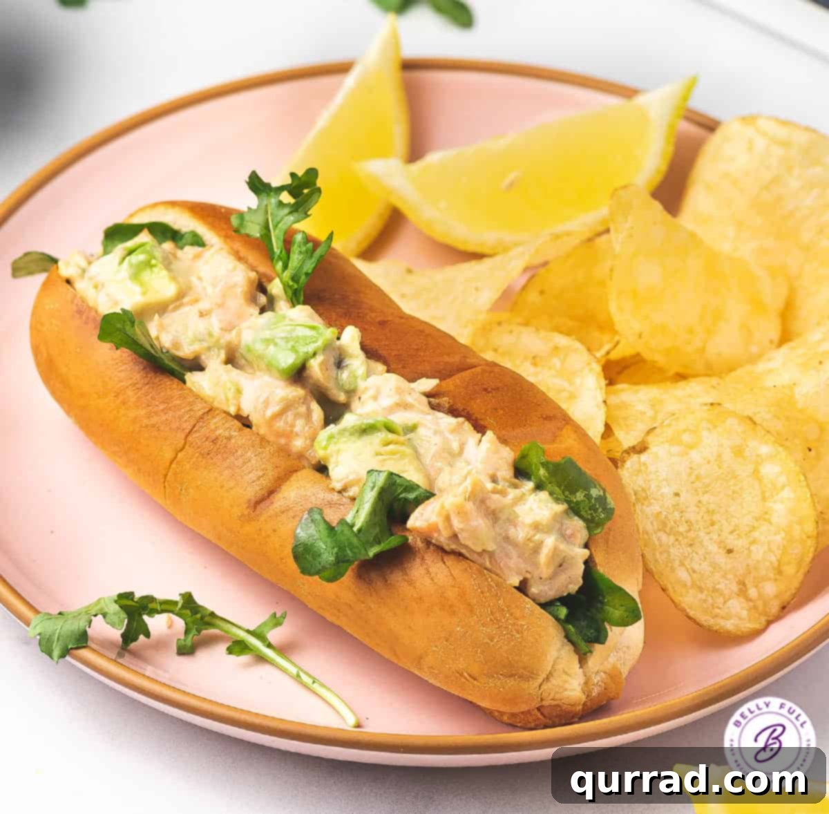 hot dog bun with salmon salad on plate with chips