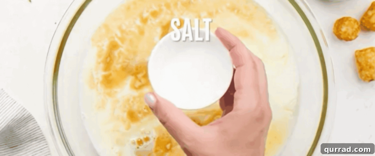 Eight large eggs being whisked together with milk and seasonings in a clear mixing bowl.