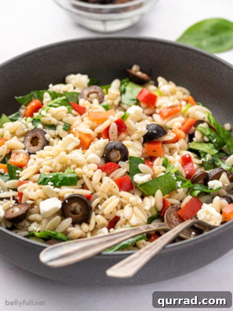 Sun-Kissed Mediterranean Orzo 4 Close-up of a bowl of Mediterranean Orzo Salad, highlighting the texture of the orzo, the freshness of the spinach, the vibrant red bell pepper, and the crumbled feta cheese.