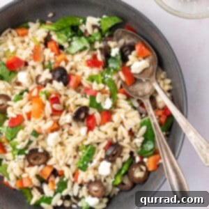 overhead bowl of Mediterranean Orzo Salad with serving spoons