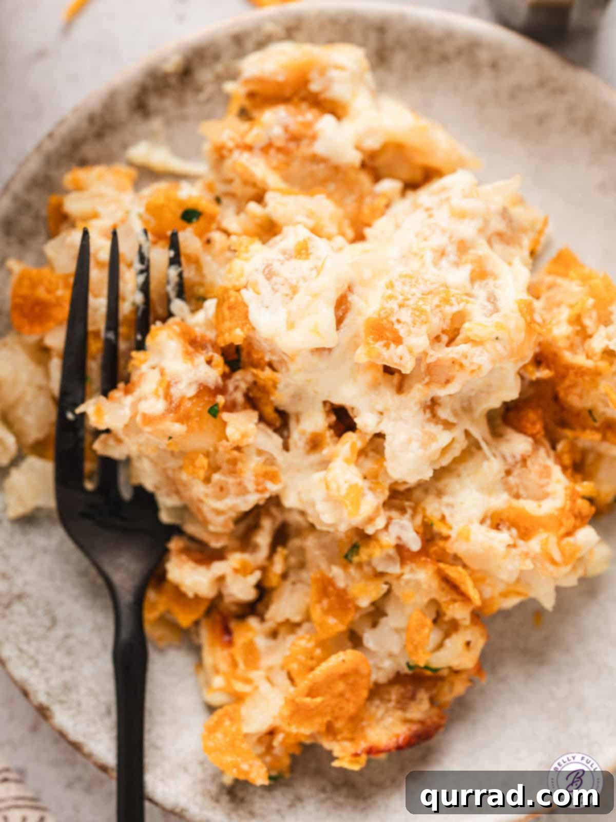 serving of cheesy party potatoes on a white plate with a fork