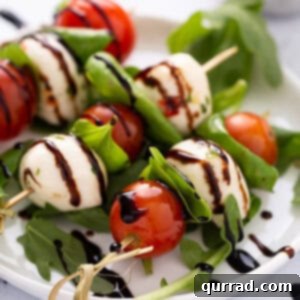 close up of 3 caprese skewer appetizers on white plate