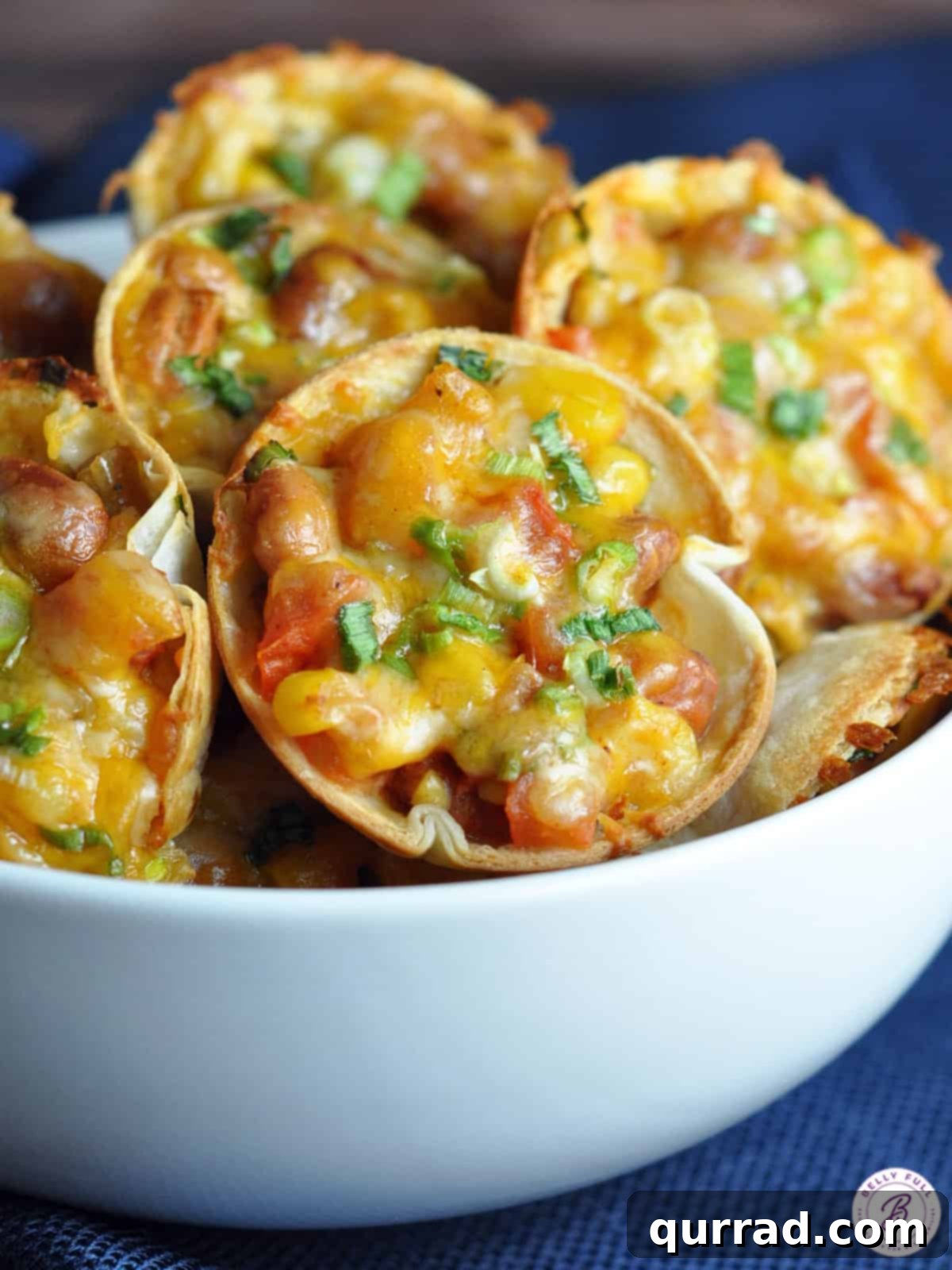 Close-up of golden brown Southwestern Saucers, showing their cheesy, bean and corn filling, in a muffin tin
