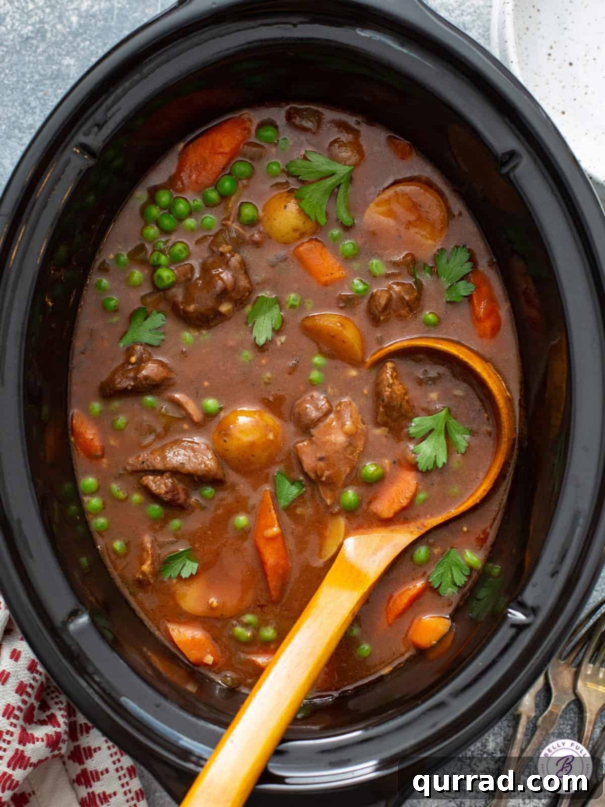 Overhead shot of hearty beef stew in a slow cooker, with a ladle resting in the pot, highlighting the tender beef and vibrant vegetables.