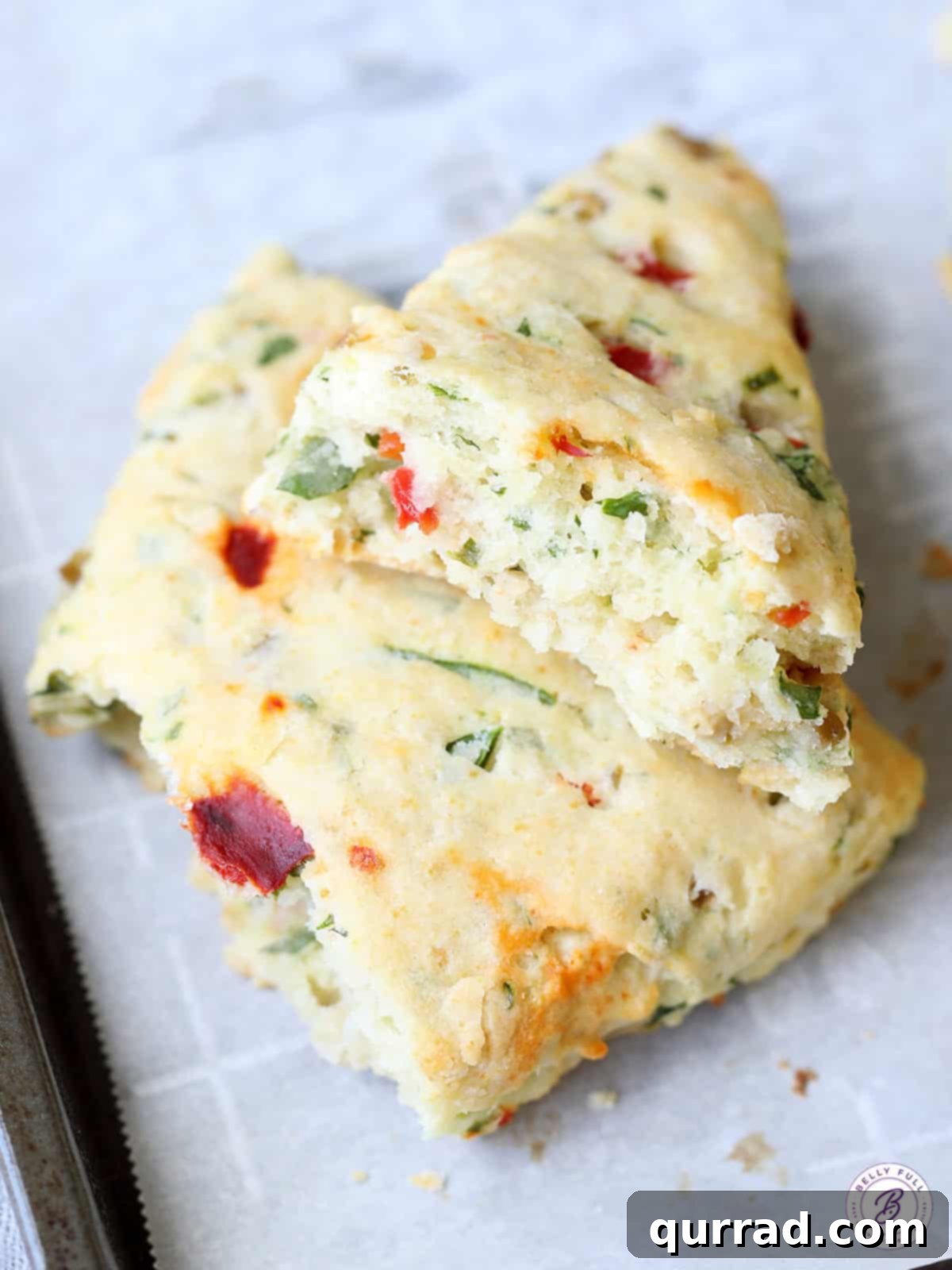 Stack of Bruschetta Scones, broken in half to show their flaky texture and delicious fillings.