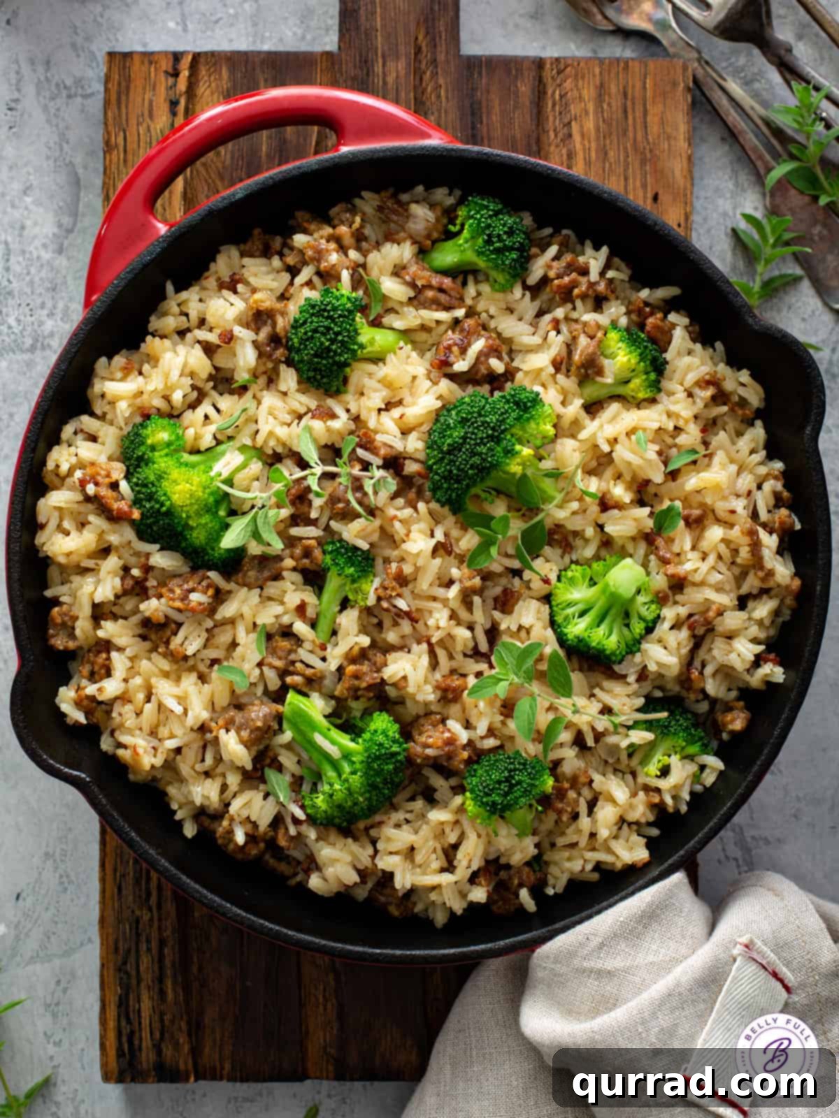 A vibrant overhead shot of a one-pot skillet filled with cooked Italian sausage, fluffy rice, and bright green broccoli florets.