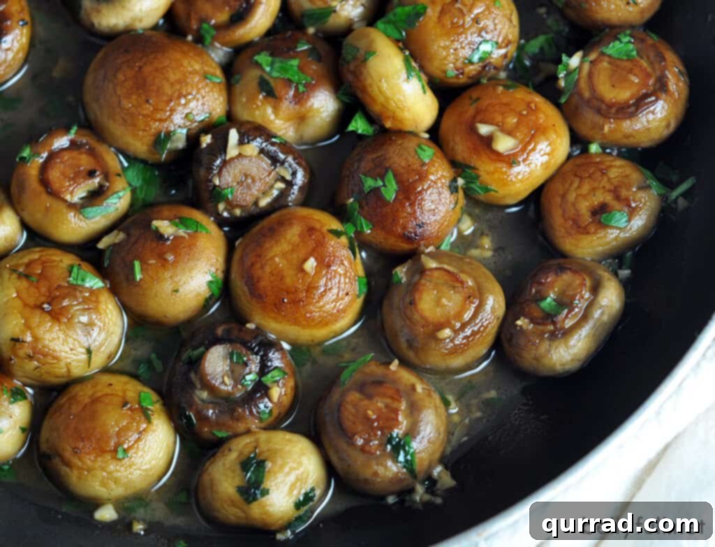 Sautéed Mushrooms with Garlic and Herbs 3 Golden-brown whole cremini and button mushrooms in a cast iron skillet, coated in a rich butter and wine sauce.