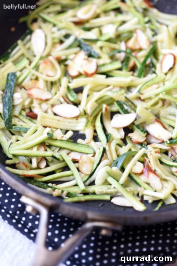 Effortless Skillet Zucchini with Garlic, Parmesan, and Almonds Skillet Zucchini Matchsticks in pan, garnished with herbs and parmesan