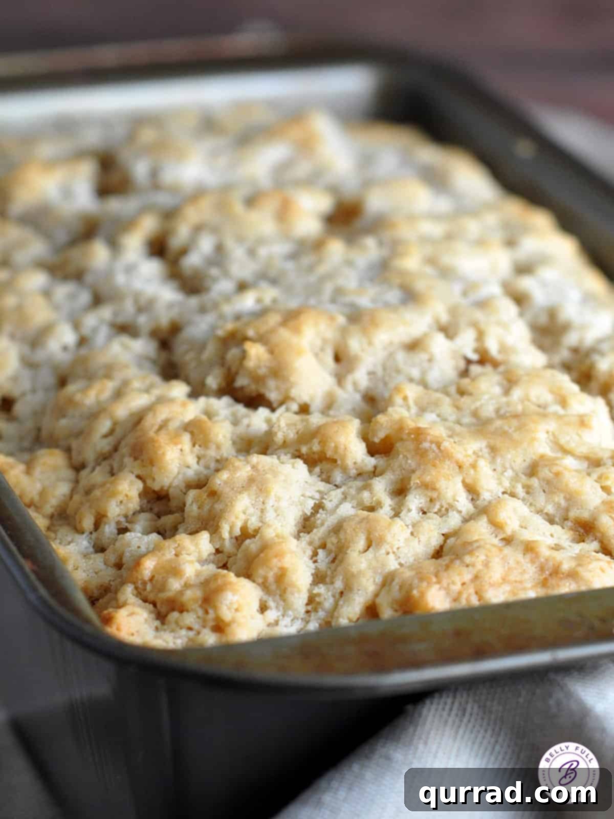 A freshly baked beer bread loaf cooling in a pan, showing its golden crust.