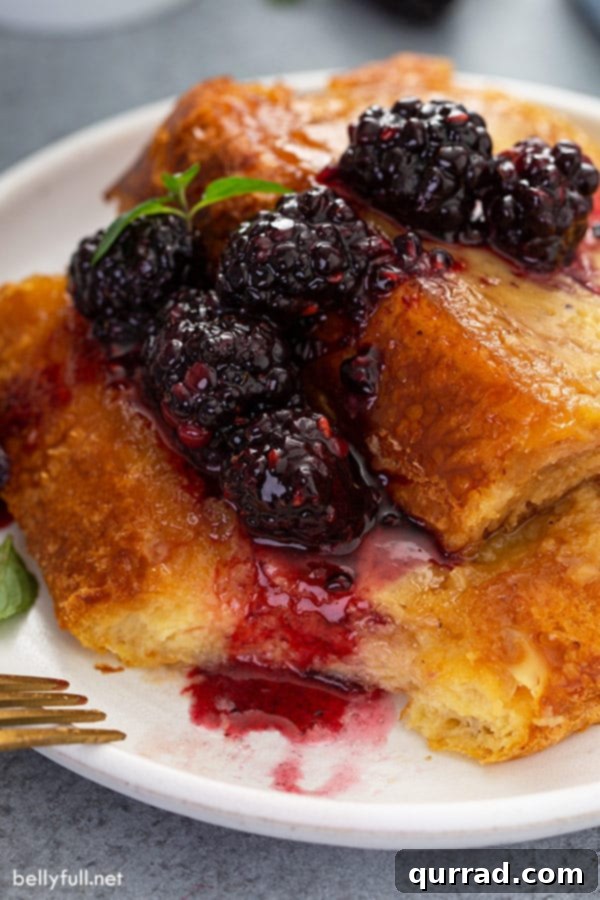 Wake Up To Brioche French Toast Casserole 2 close up Brioche French Toast with syrupy blackberries on white plate