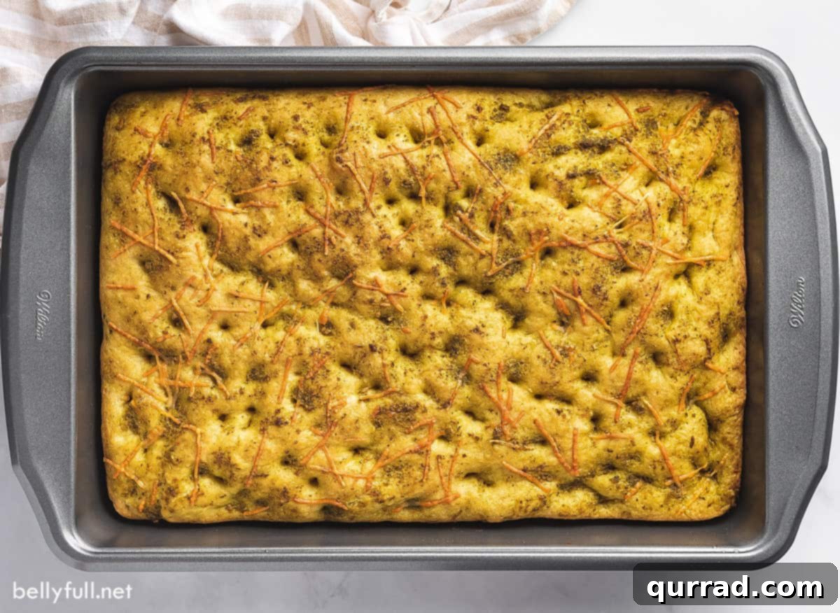 Savory Rosemary Focaccia 3 A perfectly baked focaccia loaf, golden brown and glistening with olive oil, still warm in a 9x13 inch baking pan.