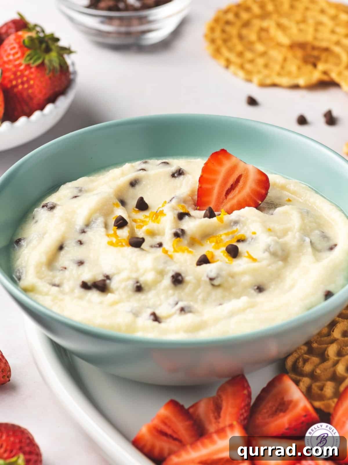 Close-up of creamy Italian ricotta dip garnished with mini chocolate chips, with fresh strawberries as dippers.