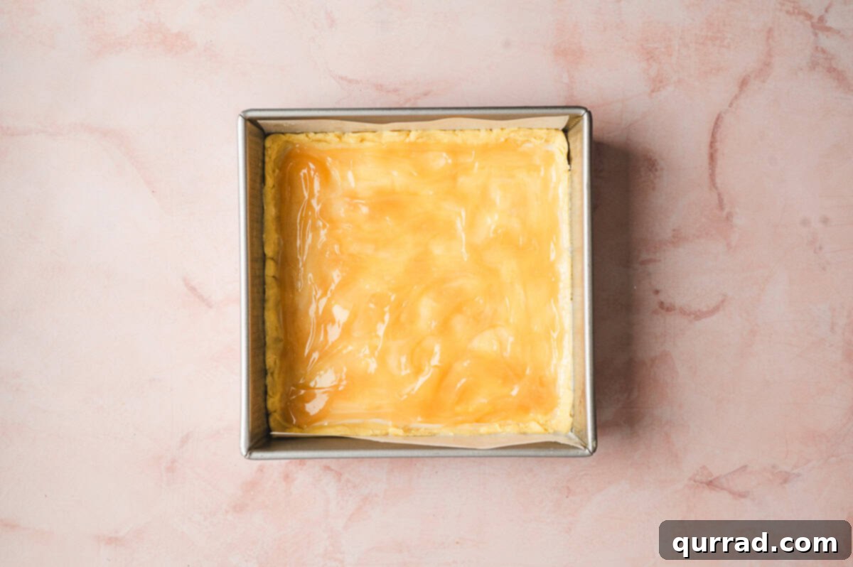 Zesty Lemon Bliss Bars 6 lemon curd spread on top of dough in a square baking dish