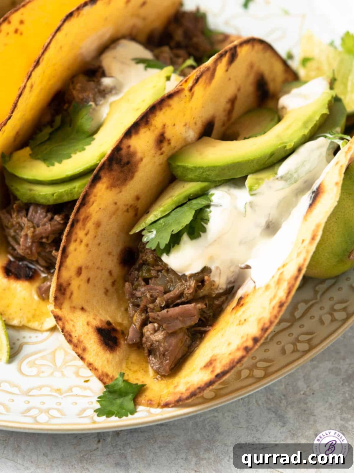 Tacos with perfectly shredded beef, topped with fresh sour cream and creamy avocado slices.