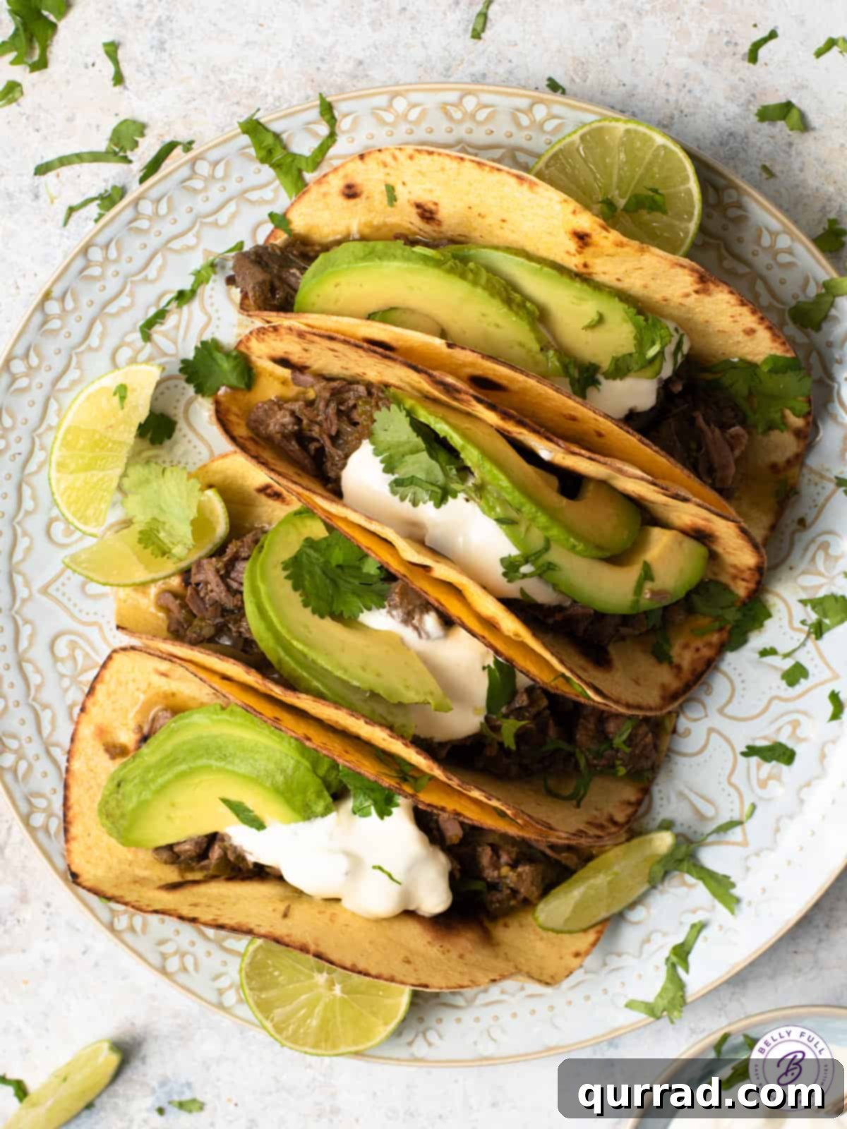 An overhead shot showcasing four delicious beef tacos adorned with avocado and lime slices.