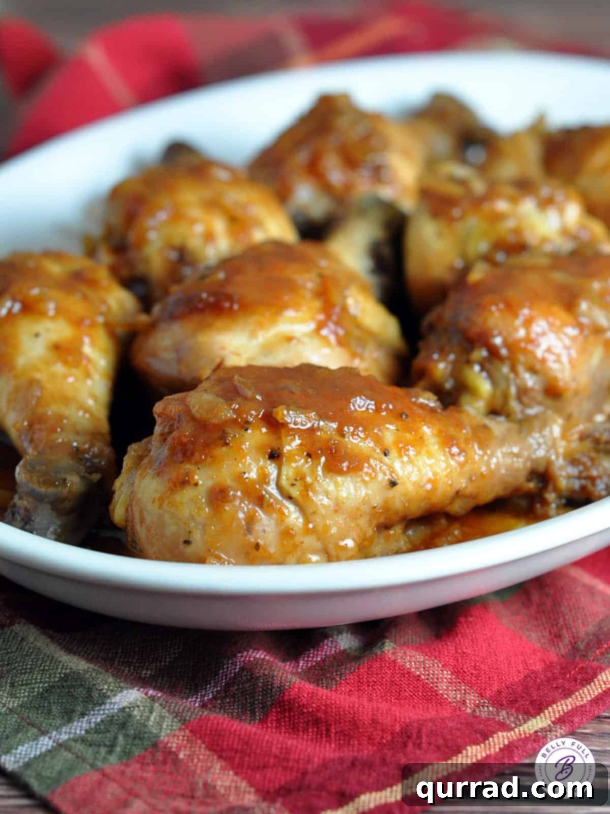 Two pieces of Slow Cooker Hurry Chicken, glistening with a rich, tangy sauce, served alongside creamy mashed potatoes on a white plate, garnished with fresh herbs.