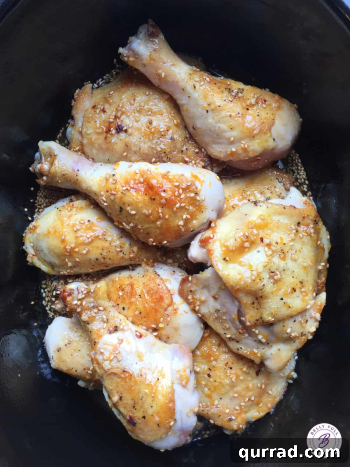 Crockpot Sticky Honey-Soy Chicken 3 Raw chicken drumsticks and thighs marinating in honey-soy sauce inside a slow cooker.