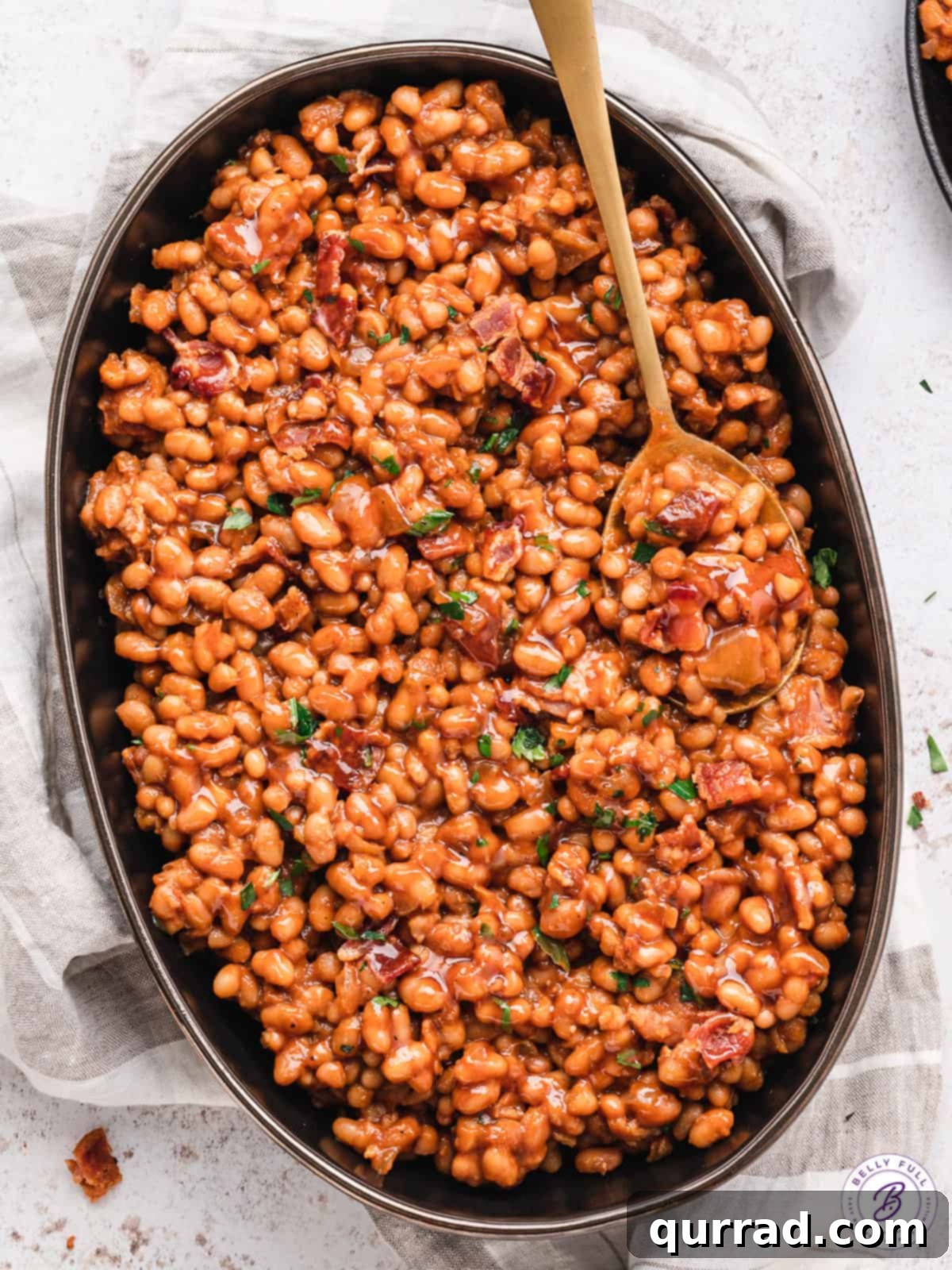Grandma's Secret Baked Beans 7 Large serving bowl of baked beans with a spoon in it.