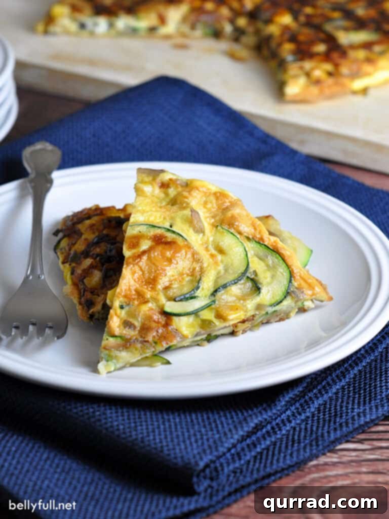 Desert Sunrise Frittata 3 A single slice of vibrant egg frittata, flecked with green zucchini and yellow corn, resting on a clean white plate.