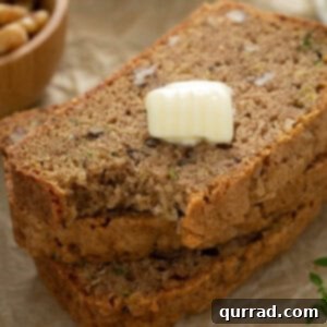 Two slices of zucchini bread, elegantly presented with a dollop of butter, highlighting its perfect texture.