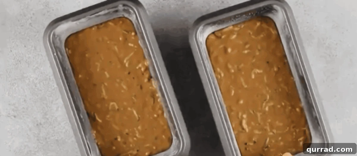 Two loaf pans filled evenly with unbaked zucchini bread batter, ready for the oven.