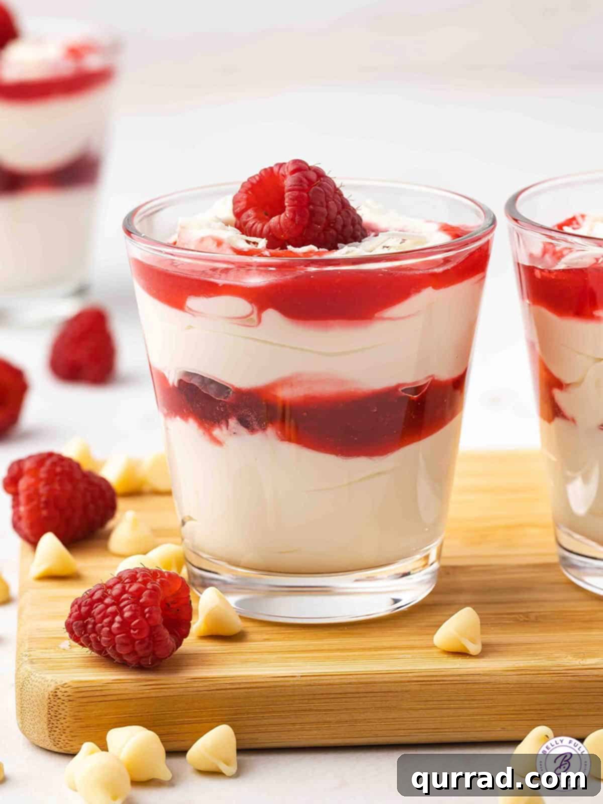 Cheesecake mousse and raspberry sauce beautifully layered in elegant parfait glasses, garnished with fresh raspberries.
