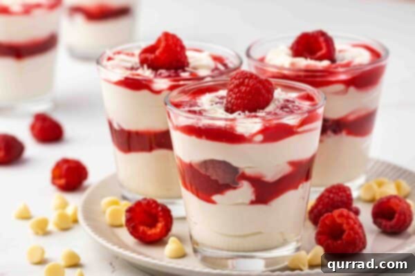 white chocolate mousse cheesecake layered with raspberry sauce in parfaits glasses, ready to serve