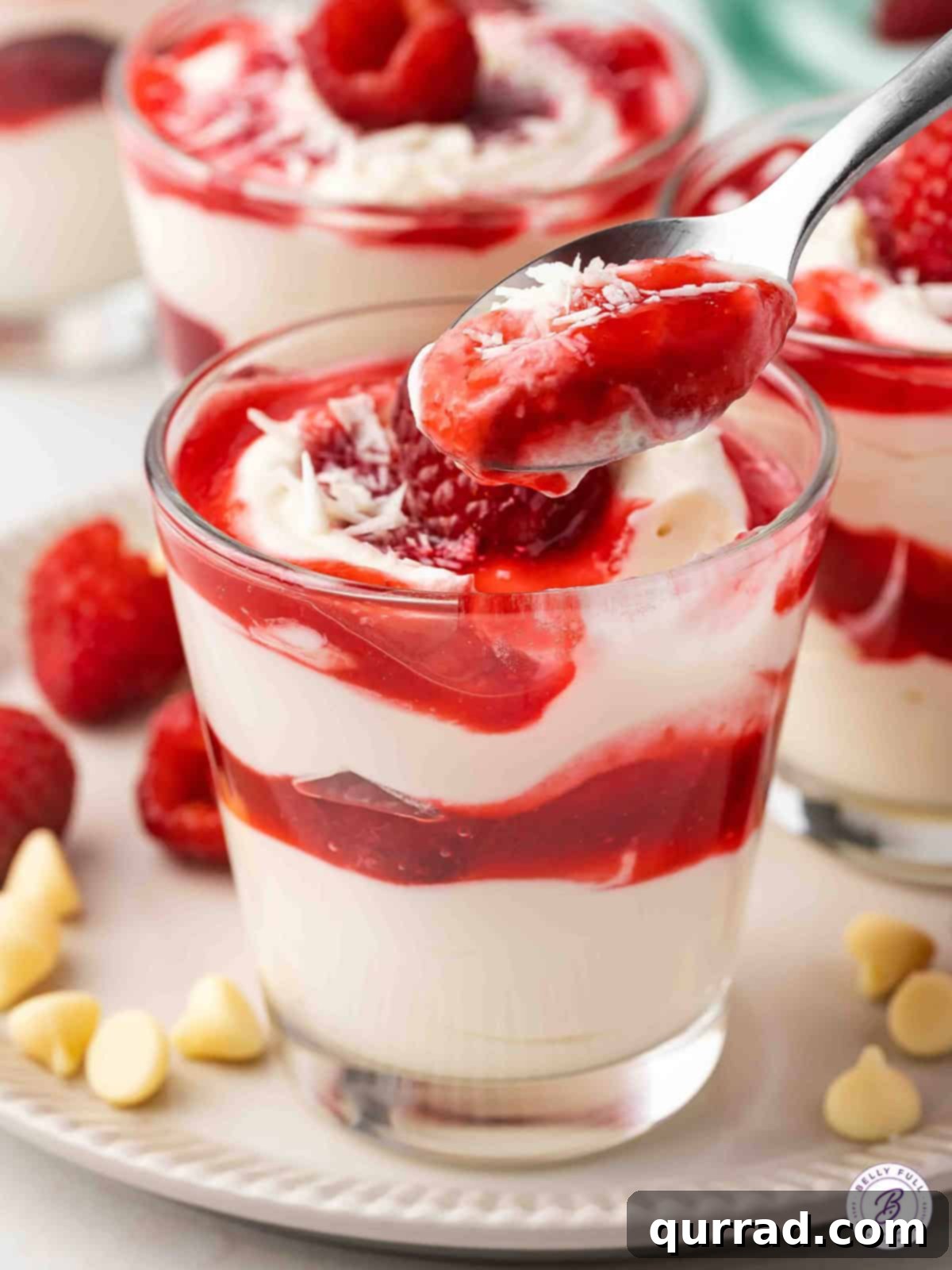 A spoonful of creamy white chocolate mousse with a swirl of vibrant raspberry sauce, highlighting the dessert's texture.