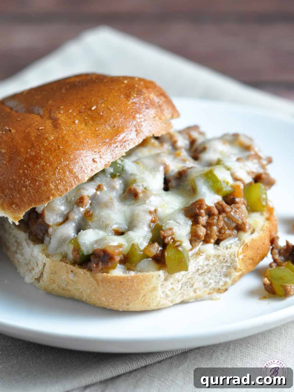 A close-up of a serving of Philly Cheesesteak Sloppy Joes, showing the rich beef mixture and melted cheese on a toasted bun.