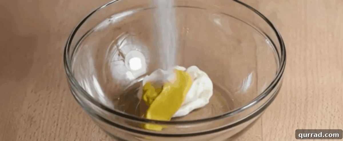 Creamy Egg Salad 6 A whisk combining mayonnaise, tangy Dijon mustard, finely diced dill pickles, and a splash of pickle juice in a glass bowl to create the creamy dressing.