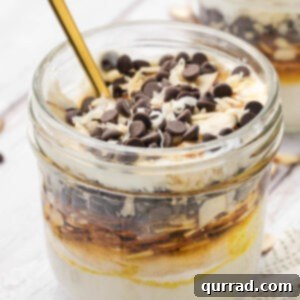 jar with spoon of a layered almond joy yogurt parfait