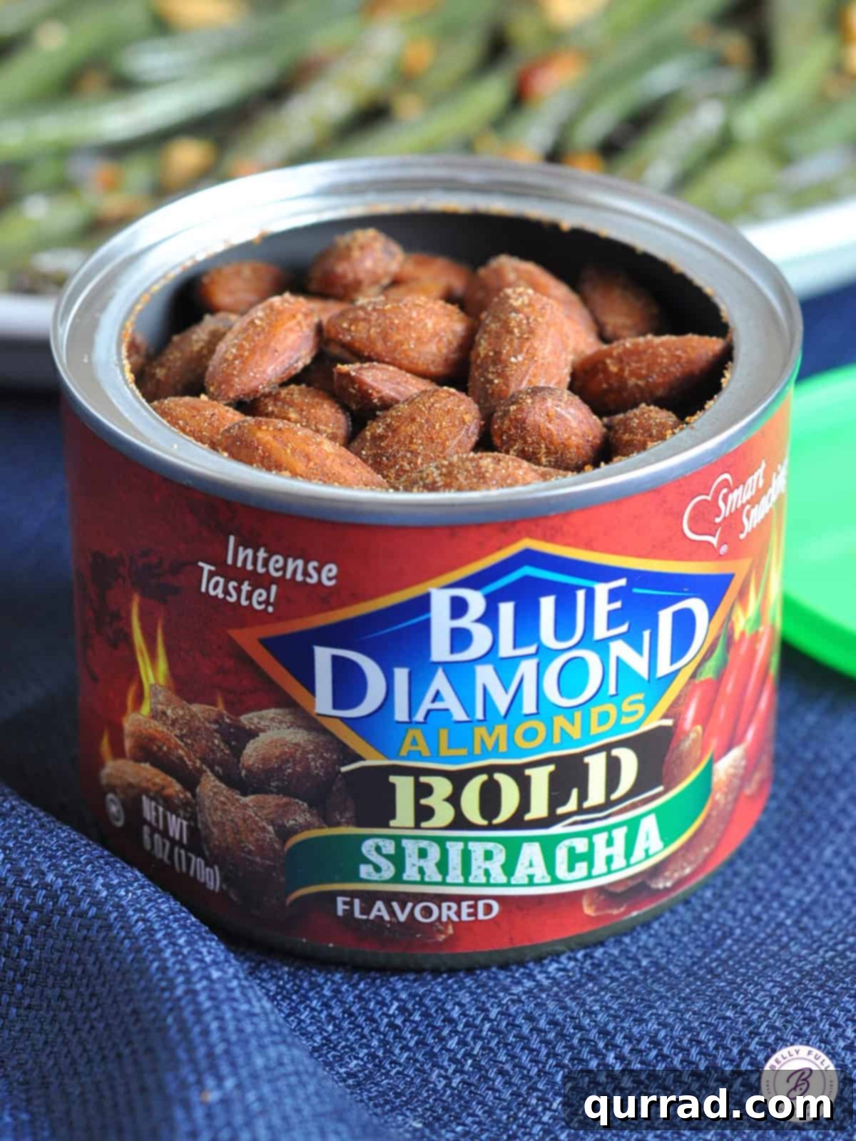 Open container of Sriracha flavored almonds, showcasing their vibrant red coating and tempting appearance.