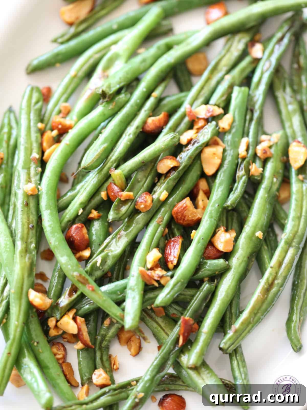 Close-up shot of crispy roasted green beans with chopped Sriracha almonds, showing the beautiful caramelization and texture.