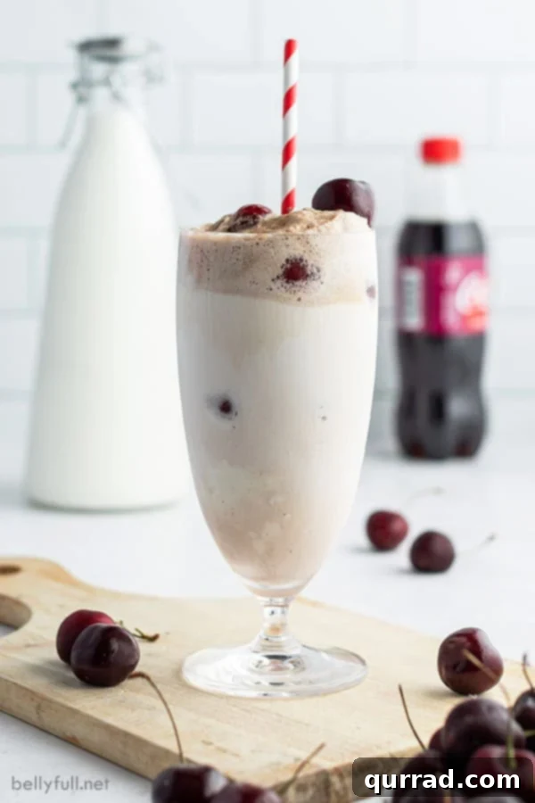 Cherry Cloud Float 3 Ice cream float in a tall glass with a red and white striped straw and fresh cherries as garnish.