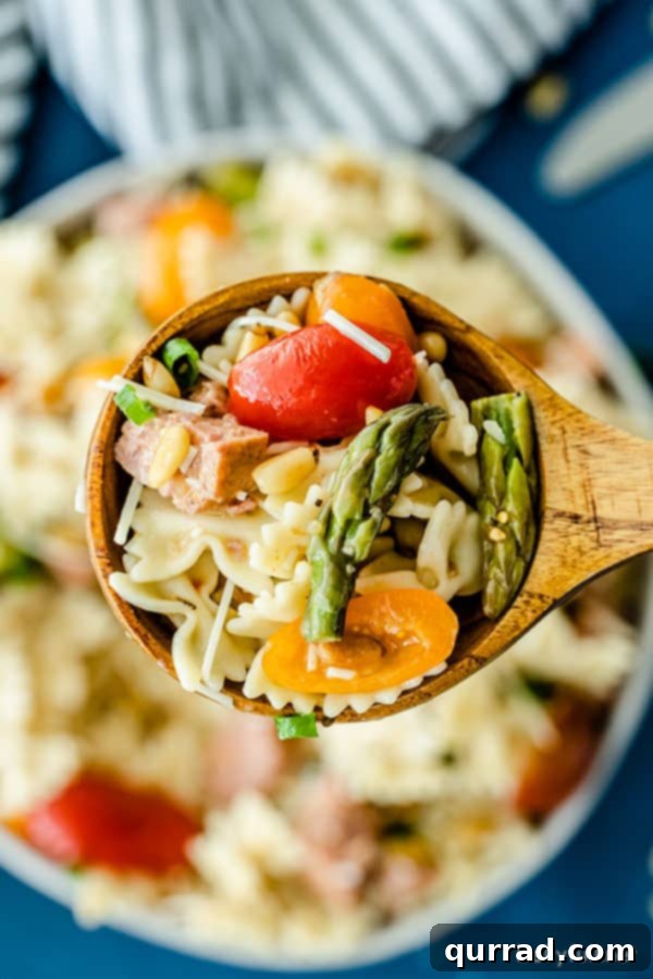 Effortless Italian Pasta Salad 2 Overhead close-up of vibrant Italian Pasta Salad on a wooden spoon, showcasing colorful vegetables and rich pasta