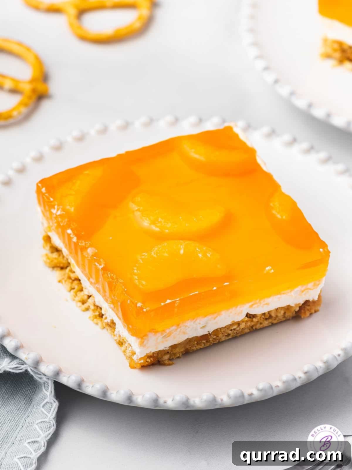 square portion of orange pretzel dessert on white plate, ready to be enjoyed