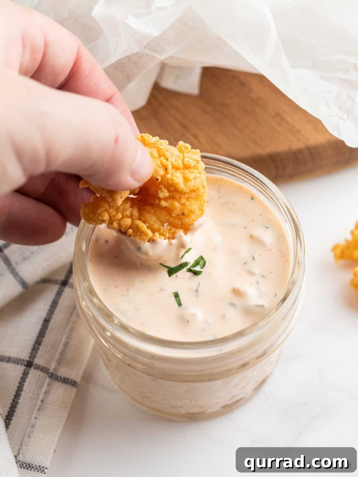 Tangy Remoulade Perfection 2 Crispy deep-fried shrimp being dipped into a bowl of rich, creamy remoulade sauce, showcasing its perfect texture and vibrant color.