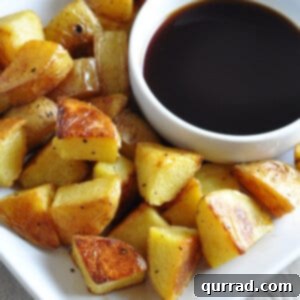 pile of roasted potatoes on plate with cup of malt vinegar