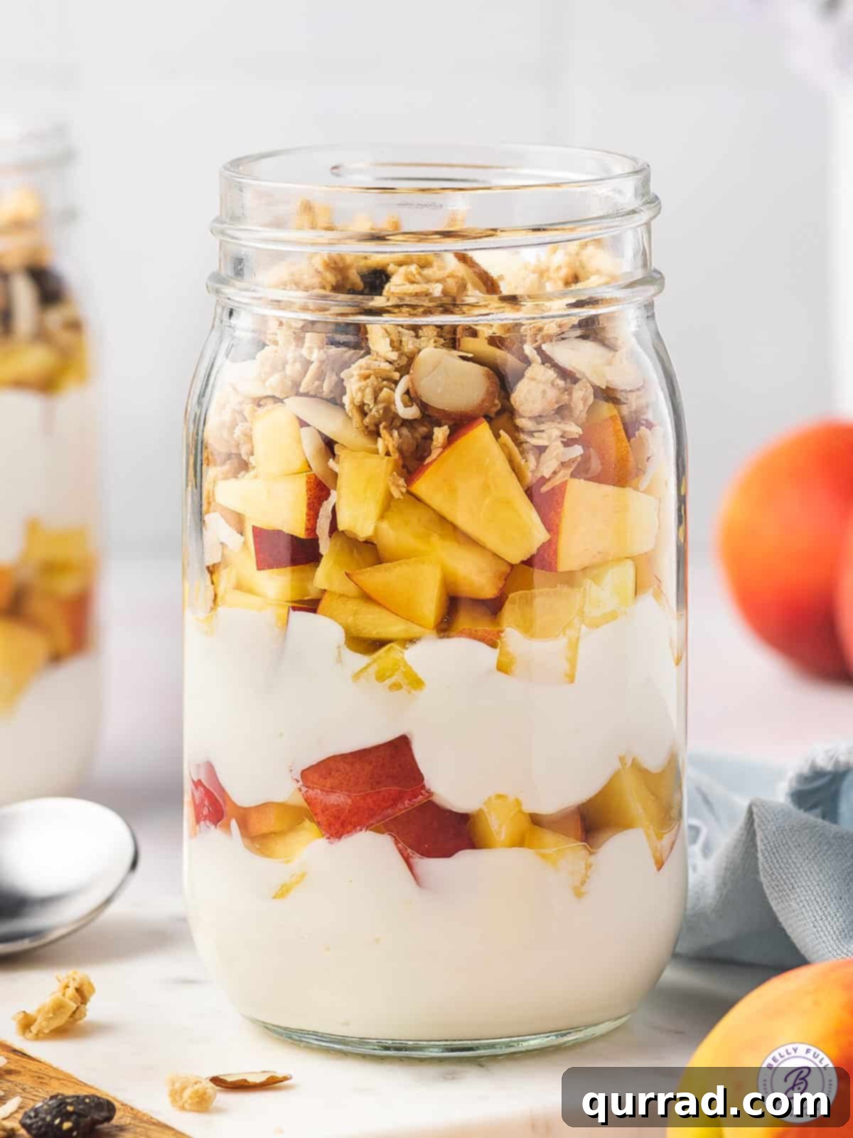 A beautifully layered glass jar of creamy peach yogurt parfait, showcasing vibrant colors and fresh ingredients, perfect for a healthy breakfast or snack.
