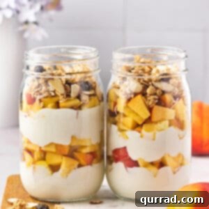 Two clear glass jars filled with layers of creamy peach yogurt, fresh peaches, and crunchy granola.