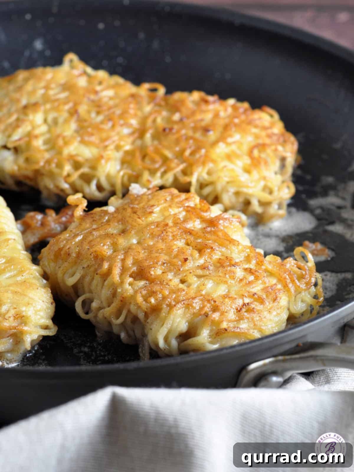 Cod in a Ramen Nest 4 Three perfectly crispy Ramen Noodle Wrapped Cod fillets cooking in a skillet, showcasing the golden-brown texture of the ramen crust