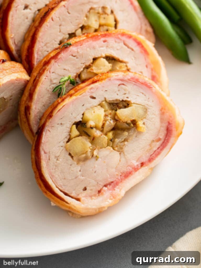 Crispy Bacon-Wrapped Pork Tenderloin 5 slices of bacon wrapped stuffed apple pork loin on white plate