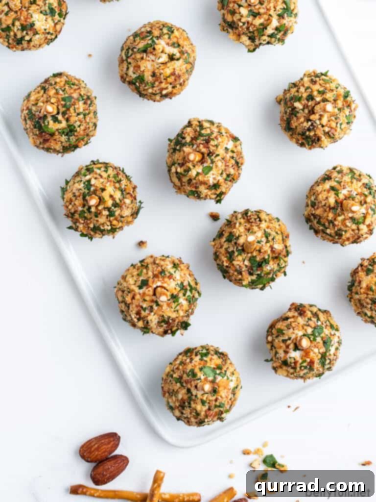 Overhead shot of a tray filled with mini cheese balls, uniformly coated in crushed almonds, arranged for an elegant presentation.