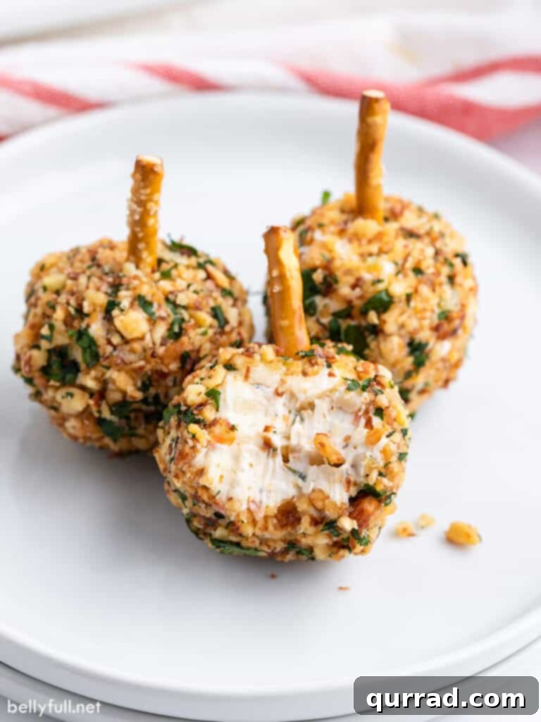 Close-up of a single mini cheese ball with a small bite taken out, revealing its creamy texture and the savory pepperoni bits within.